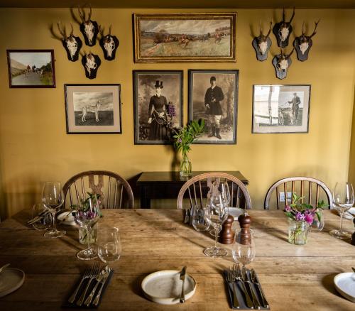 a dining room with a wooden table with chairs and pictures on the wall at George and Dragon Clifton in Penrith