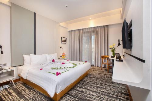 a hotel room with a bed and a television at THE 1O1 Jakarta Airport CBC in Tangerang