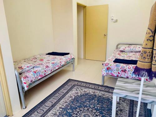 Habitación pequeña con 2 camas y alfombra. en CASA ADELIA GUESTHOUSE 2 DESA SOLEHAH en Cukai