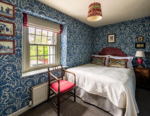 a blue bedroom with a bed and a red chair at George and Dragon Clifton in Penrith
