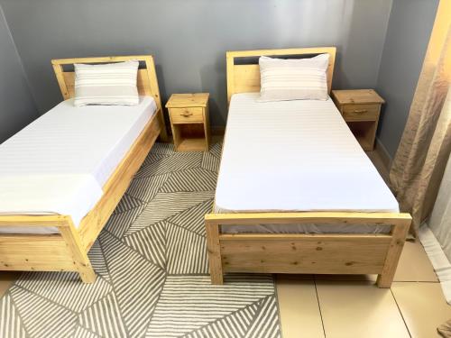 two twin beds in a room with a floor at Sally's home-near JNIA airport in Dar es Salaam