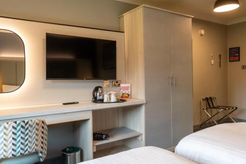 a hotel room with a bed and a tv at Warwick Conferences - Scarman in Coventry