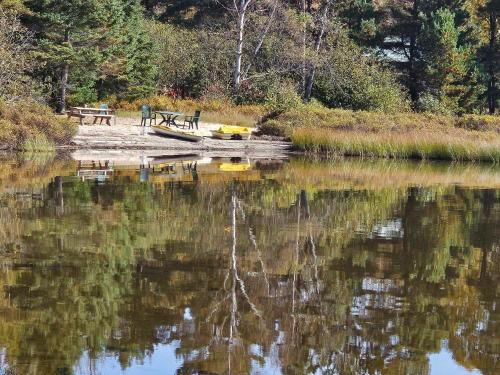 a picnic table and bench on the shore of a lake at Nelson Log Cabin in Rivière-Rouge in Rivière-Rouge