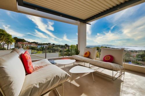 a living room with a couch and tables on a balcony at Prestigious villa with panoramic sea view in Bandol