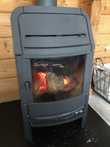 a gray stove with a fire inside of it at Vrijstaande luxe Finse blokhut 2-6 pers in Kropswolde