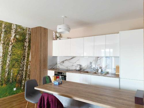 a kitchen with white cabinets and a wooden table at Parkcity Kraków pro in Krakow