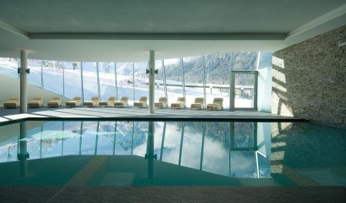 ein Zimmer mit einem Pool mit Stühlen und einem Berg in der Unterkunft Paramount Alma Suites in Sexten