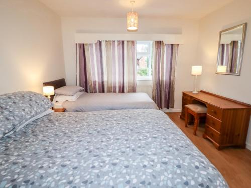a bedroom with two beds and a desk and a window at The Hawthorns in Chester