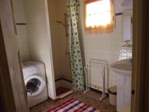 une salle de bain avec une machine à laver et un lavabo dans l'établissement PROCHE DE LA NATURE, à Mimizan