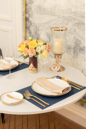 a white table with plates and a vase with flowers at CHINO@NIMMAN Luxury Boutique Hotel in Chiang Mai