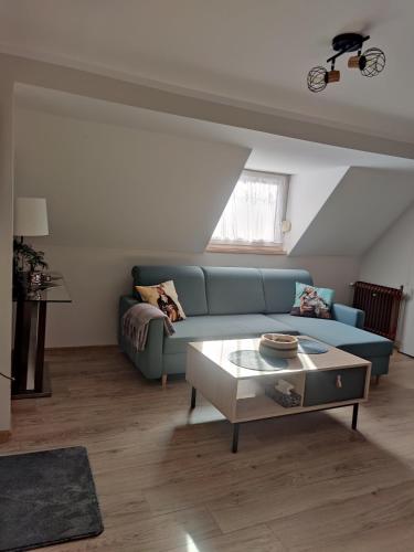 a living room with a blue couch and a table at Pod Wieżą u Kory in Siedlęcin