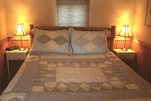 Pine Cottage at Heron Ledge في بلاتسبرغ: غرفة نوم مع سرير ومصباحين من الجهتين