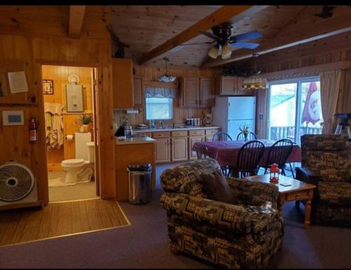 une cuisine avec un canapé, des chaises et une table dans l'établissement Augur Lake Cabin Escape, à Au Sable Forks