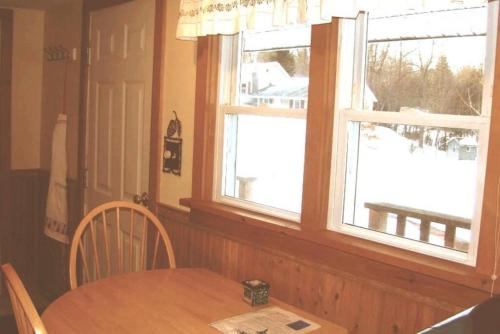 uma cozinha com uma mesa de madeira e 2 janelas em Pine Cottage at Heron Ledge em Plattsburgh