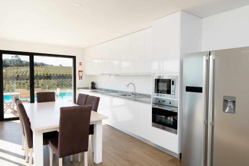 a kitchen with white cabinets and a table and chairs at Casa dos Mirtilos Draper T6 in Celorico de Basto