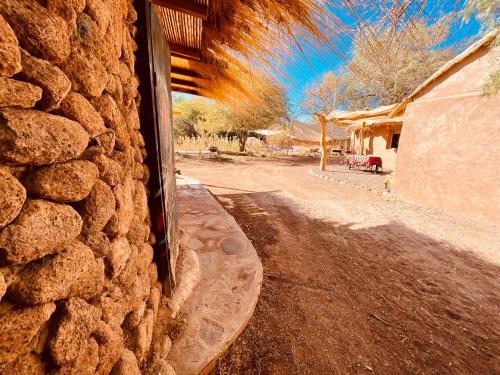 una pared de piedra junto a un camino de tierra con una casa en Cabañas Turi Lackar, en San Pedro de Atacama