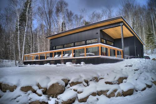 a house in the woods in the snow at KALLM-Mont-Tremblant chalet with hot tub, pond & beach on private 7acre estate in Lac-Superieur
