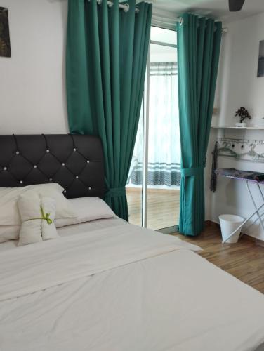 een slaapkamer met een bed met groene gordijnen en een raam bij Inap Idaman 7 5 Pax 2 Queen Plus 1 Sofa Bed in Kota Bharu