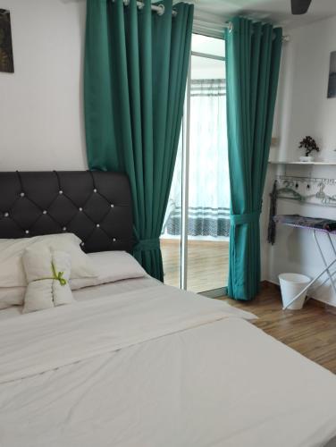 Un dormitorio con una cama con cortinas verdes y una ventana. en Inap Idaman 7 5 Pax 2 Queen Plus 1 Sofa Bed, en Kota Bharu