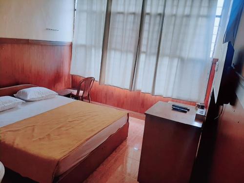 a hotel room with a bed and a table and window at Vega Residency And Bike Rentals in Madikeri