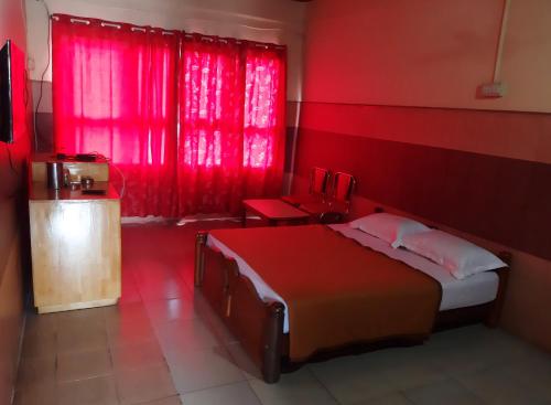 a red bedroom with a bed and a red window at Vega Residency And Bike Rentals in Madikeri