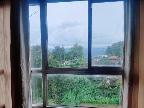 an open window with a view of a forest at Vega Residency And Bike Rentals in Madikeri