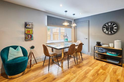 een eetkamer met een tafel en stoelen en een klok bij Host & Stay - Narrowgate Apartments in Alnwick
