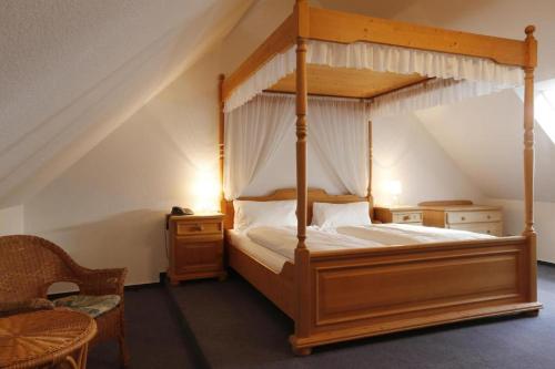 a bedroom with a canopy bed and a chair at Hotel Lüttje Burg in Lütjenburg