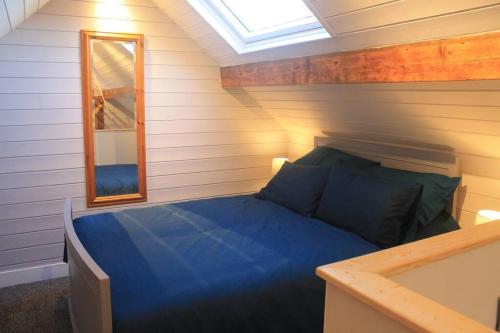a bedroom with a blue bed and a mirror at The Scullery - a quirky annex with wood fire in Huddersfield