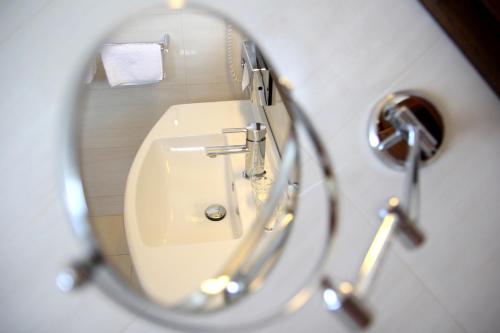 a reflection of a bathroom sink in a mirror at Hotel Baltaci Atrium in Zlín