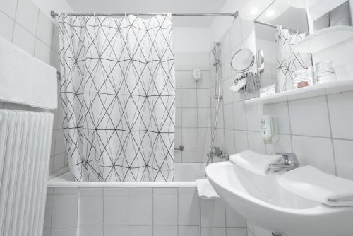 a white bathroom with a shower and a sink at Hotel Lüttje Burg in Lütjenburg