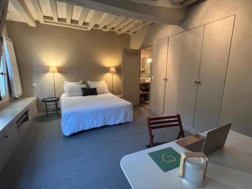 Schlafzimmer mit einem Bett und einem Schreibtisch mit einem Laptop in der Unterkunft La Clé d'Anne in Saint-Germain-en-Laye
