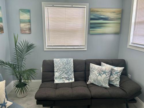 a couch in a living room with two windows at Cocoa, Beach house in Cocoa