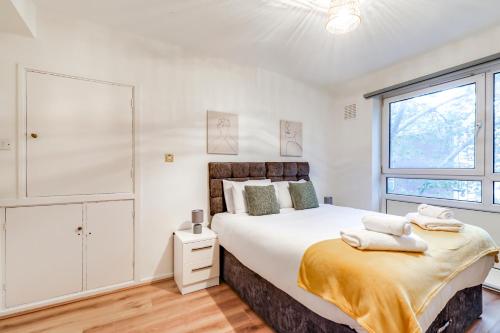 um quarto branco com uma cama grande e uma janela em Central NW1 London Apartment! em Londres