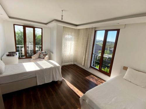 een slaapkamer met 2 bedden en grote ramen bij Airport Villa hotel in Arnavutköy