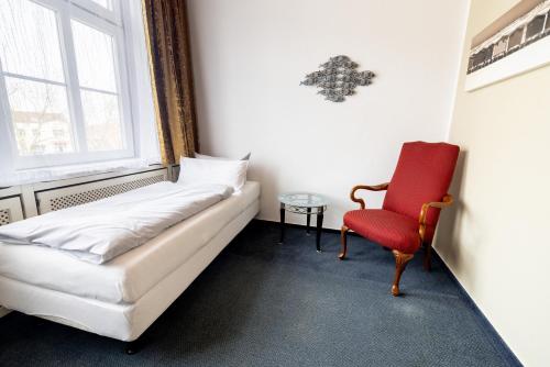 a room with a bed and a red chair at Hotel Lüttje Burg in Lütjenburg