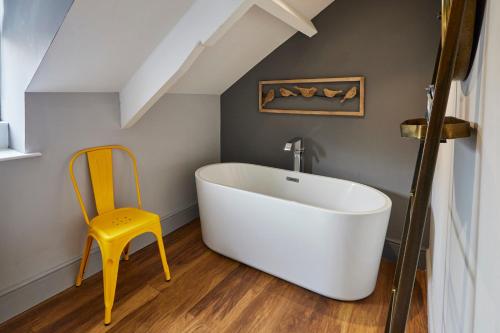 a bathroom with a white tub and a yellow chair at Host & Stay - Narrowgate Apartments in Alnwick