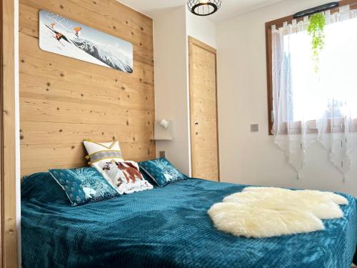 une chambre avec un lit bleu avec un mur en bois dans l'établissement Moderne appartement 4 pers avec balcon sud, parking et WiFi - à 200m des pistes et navette - FR-1-623-255, aux Gets
