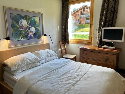 - une chambre avec un lit et un ordinateur sur une commode dans l'établissement Appartement 3* aux Gets, proche des pistes, balcon et terrasse, offre tout confort ! - FR-1-623-250, aux Gets