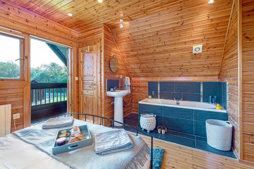a wooden bathroom with a tub and a sink at Scandi Cabin in Heart of Anglesey with Parking in Llanfairpwllgwyngyll