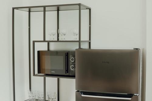 - un four micro-ondes au-dessus d'un réfrigérateur avec des verres à vin dans l'établissement Apartmán EMILY, à Brezno