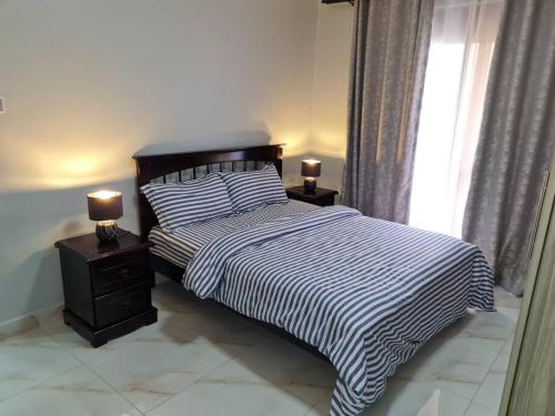 a bedroom with a bed and two night stands with lamps at Cozy Apartment in Kololo in Kampala