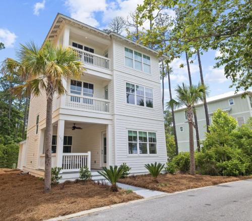 a white house with palm trees in front of it at Scissortail at Treetop in Santa Rosa Beach