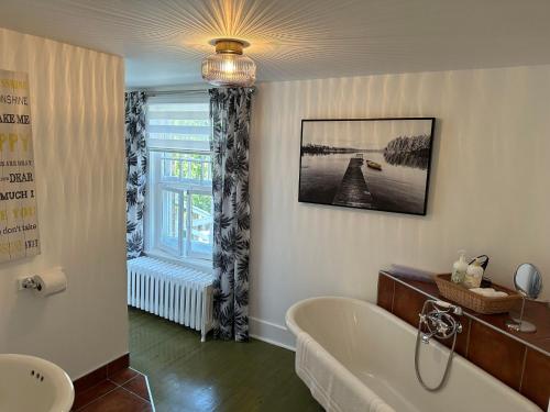 a bathroom with a bath tub and a window at Hôtel Le Rustique in Saint-Irénée