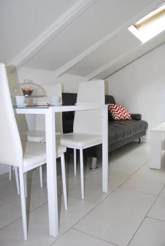 a white dining room table with white chairs and a couch at Tourist House Bologna - Self check-in in Bologna