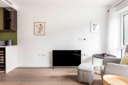 uma sala de estar branca com uma televisão e uma mesa em Modern Chelsea Apartment em Londres