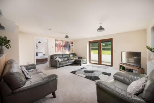 a living room with leather couches and a flat screen tv at Robins Rest - Pets welcome - Free Parking - Backgarden in Perranporth
