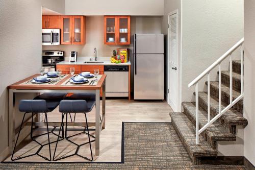 a kitchen with a table with chairs and a refrigerator at Residence Inn Los Angeles LAX/Manhattan Beach in Manhattan Beach