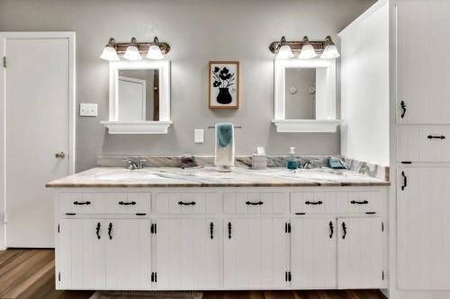 La salle de bains blanche est pourvue d'un lavabo et de deux miroirs. dans l'établissement New Cozy Retreat Located 15 minutes to Waco, à Hewitt