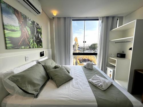 a bedroom with a large white bed with a large window at Hotel Recanto dos Dinossauros in Penha
